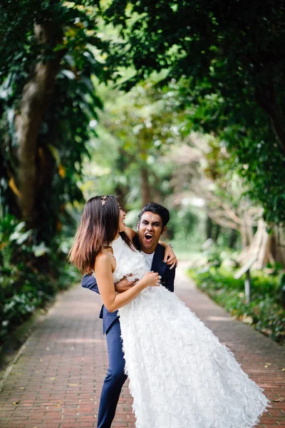 Portrait of interracial couple taking wedding photos in a beautiful park in the day. An Indian man and his Chinese fiance  on a pathway.