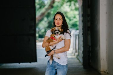 Genç bir kız ve köpeği portresi. Pan Asya kadın çekici ve raslantı giyimli ve onun Shih Tzuh onun kollarında taşıyor ve yumuşak gülümsüyor.
