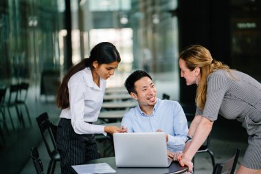 farklı bir takım 3 kişi bir dizüstü bilgisayar etrafında bir tartışma gün açık bir alanda yaşıyorsanız. Gülümse ve konuşmak gibi enerjik ve neşeli vardır.