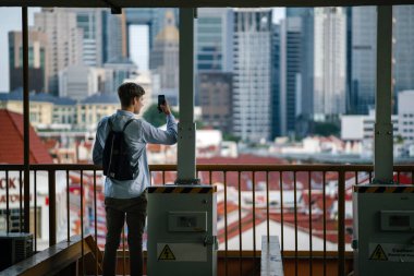 Açık havada duran genç çekici beyaz erkek portresi akıllıca telefon ile giyinmiş 