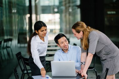 farklı bir takım 3 kişi bir dizüstü bilgisayar etrafında bir tartışma gün açık bir alanda yaşıyorsanız. Gülümse ve konuşmak gibi enerjik ve neşeli vardır.