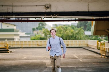 Asya araba parkında gün batımında kameraya Sprint bir genç ve yakışıklı beyaz genç dinamik portresi.