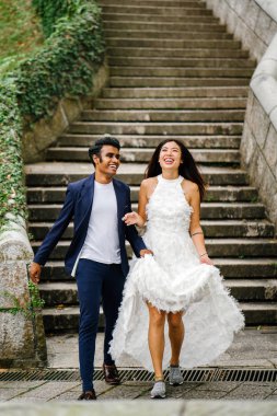 Interracial aşıklar çifti parkta taş merdivenlerden gün boyunca çalıştırın. Bir Hintli Çinli bir kadını evleniyor ve onlar zevk ve neşe içinde merdivenlerden aşağı çalışan.