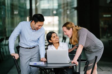 farklı bir takım 3 kişi bir dizüstü bilgisayar etrafında bir tartışma gün açık bir alanda yaşıyorsanız. Gülümse ve konuşmak gibi enerjik ve neşeli vardır.