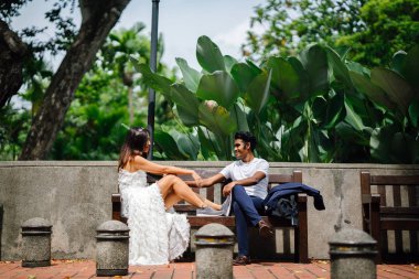 Gelin ve damat parkta bir bankta rahat bir anı paylaşın. Onlar farklı kültürlerden gelen bir ırklararası çift, bir Hint biri diğer Çinli bir kadını adam.