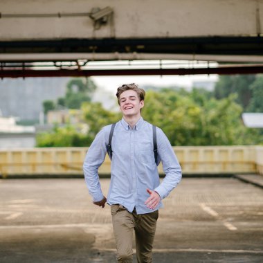 Asya araba parkında gün batımında kameraya Sprint bir genç ve yakışıklı beyaz genç dinamik portresi.