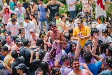 Singapur, 3 Mart 2018: Sentosa Island, Singapur bayram kutlama. Hintliler ve diğer kutlama renkli hamur ve toz birbirlerine yayma ve güneşin büyük bir havuzu müzik dans.