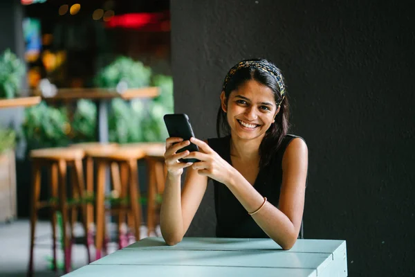 一个有吸引力和年轻的印度亚裔职业女性的坦率的肖像 阅读她的平板电脑或电子阅读器 她在温暖 舒适的咖啡馆或 Coworking 她在读她的平板电脑时微笑着 — 图库照片