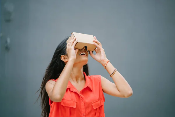 A young and photogenic Indian woman tries virtual reality goggles for the first time. She is smiling and laughing in delight and surprise at the experience