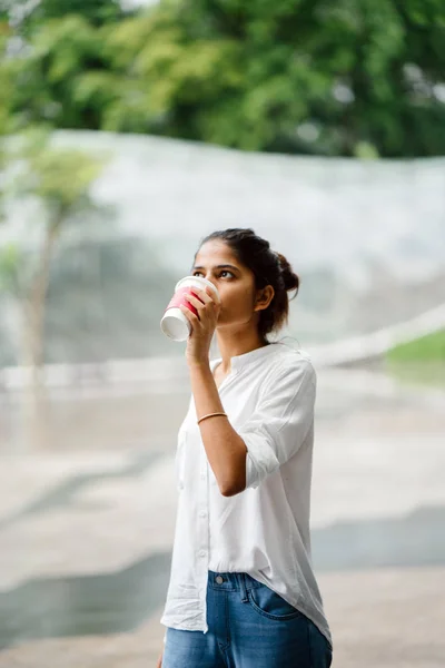 カフェ コーヒー ショップ の日にコーヒー カップを持って外に立って笑顔若い インド アジア女性の肖像 — ストック写真