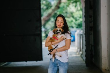 Genç bir kız ve köpeği portresi. Pan Asya kadın çekici ve raslantı giyimli ve onun Shih Tzuh onun kollarında taşıyor ve yumuşak gülümsüyor.