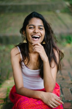 Günde bir parkta oturan çekici, genç Hint (Asya) kadın portresi adımlar.