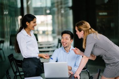 farklı bir takım 3 kişi bir dizüstü bilgisayar etrafında bir tartışma gün açık bir alanda yaşıyorsanız. Gülümse ve konuşmak gibi enerjik ve neşeli vardır.