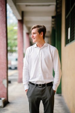 Stüdyo portre gülümseyen genç bir beyaz adam. İş rahat giyiniyor. O genç, yakışıklı, fotojenik ve mutlu, kendine güvenen ve heyecanlı görünüyor.