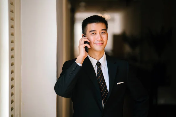 Portrait of young and handsome Chinese Asian man in a suit with his smartphone.