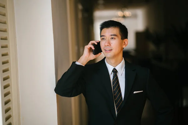 Portrait of young and handsome Chinese Asian man in a suit with his smartphone.