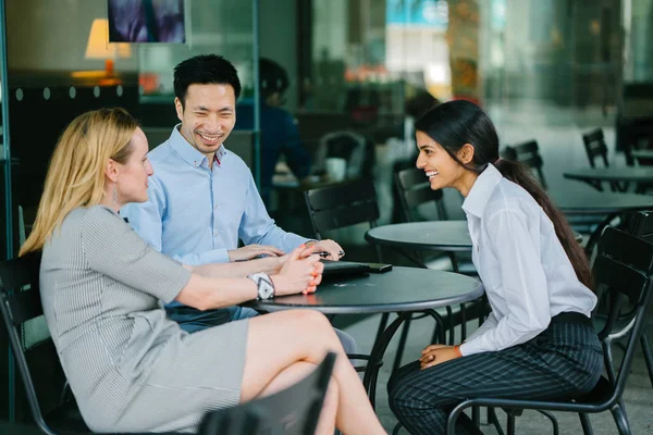 young Indian Asian woman is interviewing for a job and is speaking with a diverse interview panel in an office in the day. One interviewer is a Chinese man and the other a caucasian woman.