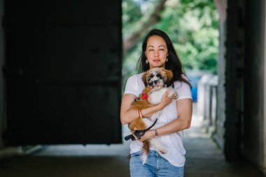 Genç bir kız ve köpeği portresi. Pan Asya kadın çekici ve raslantı giyimli ve onun Shih Tzuh onun kollarında taşıyor ve yumuşak gülümsüyor.
