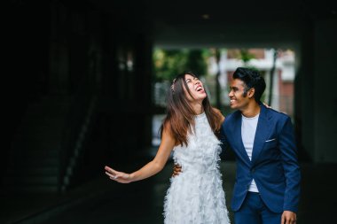  genç bir ırklararası çift evleniyor portresi. Bir Hint ve Çin onun karı koca gün karanlık bir arka plan karşı cadde boyunca bir fotoğraf için poz.