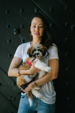 Genç bir kız ve köpeği portresi. Pan Asya kadın çekici ve raslantı giyimli ve onun Shih Tzuh onun kollarında taşıyor ve yumuşak gülümsüyor.