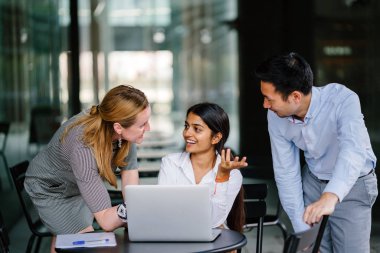 farklı bir takım 3 kişi bir dizüstü bilgisayar etrafında bir tartışma gün açık bir alanda yaşıyorsanız. Gülümse ve konuşmak gibi enerjik ve neşeli vardır.