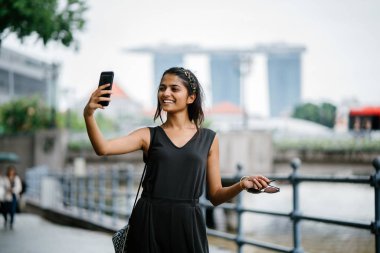 Genç Hintli kadın kendini selfie fotoğrafta onu smartphone ile cityscape arka planda alır..