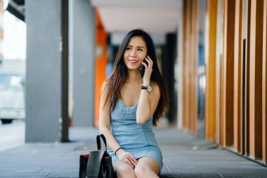 Bir genç, fotojenik ve çekici Çinli Asyalı kadın ile o günlerde Asya'da bir sokakta randevusu için beklediği sırada smartphone portresi. O gülümsüyor ve mutlu görünüyor.