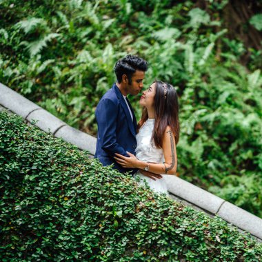 Farklı ırkların çekici bir çift stand birlikte parkta günde Asya'da. Düğün fotoğrafları götürüyorlar. Hintli bir adam, diğer Çinli bir kadını biri.
