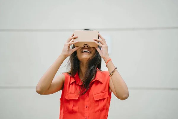 A young and photogenic Indian woman tries virtual reality goggles for the first time. She is smiling and laughing in delight and surprise at the experience
