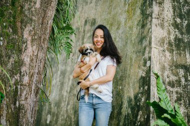Onun genç shih tzuh yavru köpek park ile gün içinde oturan genç Pan Asya kadın portresi. Gülümsüyor ve her ikisi de sıcak gün tadını çıkarıyor.