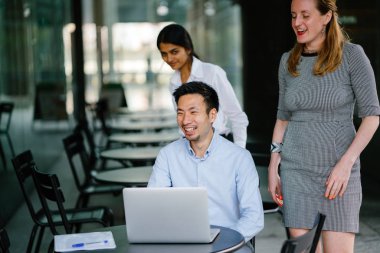 farklı bir takım 3 kişi bir dizüstü bilgisayar etrafında bir tartışma gün açık bir alanda yaşıyorsanız. Gülümse ve konuşmak gibi enerjik ve neşeli vardır.