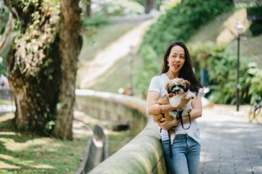Parkta onun shih tzuh köpek olan bir genç, çekici pan Asya kadın portresi. Onlar ortasında bir yürüyüş ve neşeli ve rahat görünüyorlar.