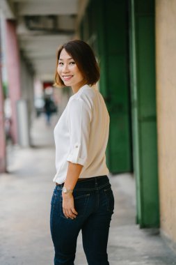 Asya bir Çinli kadın Yöneticisi gün ayakta portresi. O gün bir koridorda duran ve güvenle gülümseyen.