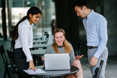 farklı bir takım 3 kişi bir dizüstü bilgisayar etrafında bir tartışma gün açık bir alanda yaşıyorsanız. Gülümse ve konuşmak gibi enerjik ve neşeli vardır.