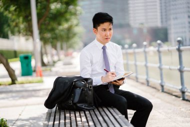 Bir defter Singapur Nehri boyunca onun dolma kalem ile gün içinde yazılı Asya adam portresi. O profesyonel bir beyaz gömlek giymiş, ama onun ceket kravat vardır.