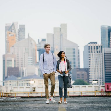 Genç çekici çift ayakta birlikte gündüzleri portresi. Hint ve erkek beyaz kadındır. Her ikisi de kayıtsızca giyinmiş ve gülümsüyor musun.