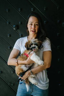 Genç bir kız ve köpeği portresi. Pan Asya kadın çekici ve raslantı giyimli ve onun Shih Tzuh onun kollarında taşıyor ve yumuşak gülümsüyor.