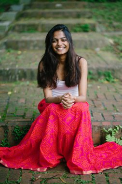 Günde bir parkta oturan çekici, genç Hint (Asya) kadın portresi adımlar.