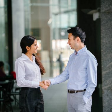 İki profesyonel iş adamları şehirde bir ofiste el sıkışın. Bir Hint kadının elleri bir Çinli ile sözleşmesinde sallıyor ve bunlar gülümseyen ve profesyonel olarak giyinmiş.