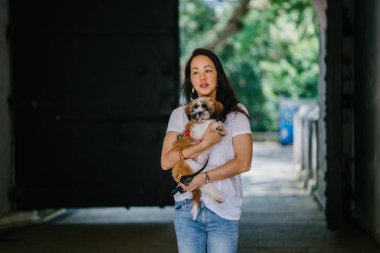Genç bir kız ve köpeği portresi. Pan Asya kadın çekici ve raslantı giyimli ve onun Shih Tzuh onun kollarında taşıyor ve yumuşak gülümsüyor.