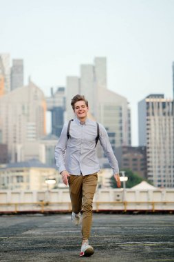 Asya araba parkında gün batımında kameraya Sprint bir genç ve yakışıklı beyaz genç dinamik portresi.