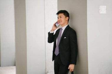 Genç yakışıklı işadamı portresi bir resmi takım elbise ve kravat giymiş... O onun smartphone vasıl aşağı bakıyor. O akıllı ve kendinden emin görünüyor.