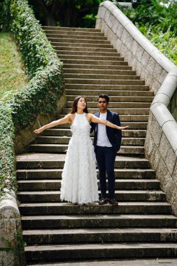 Interracial aşıklar çifti parkta taş merdivenlerden gün boyunca çalıştırın. Bir Hintli Çinli bir kadını evleniyor ve onlar zevk ve neşe içinde merdivenlerden aşağı çalışan.
