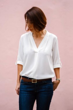 Stüdyo düz pembe arka plan karşı bir Çinli Asyalı kadın portresi. O zarif bir beyaz bluz ve kot pantolon (casual akıllı) bir bob ile giyinmiş ve o (uçan saç kamçı gibi gülümsüyor)