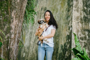 Onun genç shih tzuh yavru köpek park ile gün içinde oturan genç Pan Asya kadın portresi. Gülümsüyor ve her ikisi de sıcak gün tadını çıkarıyor.
