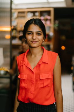 Kameraya gülümseyen bir genç ve çekici Hint Asyalı kadın portresi. O akıllı rahat giyinmiş ve rahat ve neşeli.