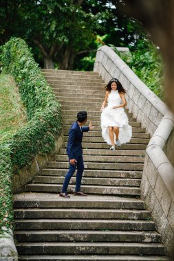 Interracial aşıklar çifti parkta taş merdivenlerden gün boyunca çalıştırın. Bir Hintli Çinli bir kadını evleniyor ve onlar zevk ve neşe içinde merdivenlerden aşağı çalışan.