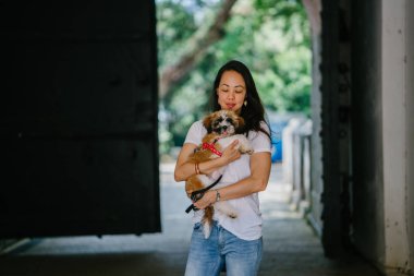 Genç bir kız ve köpeği portresi. Pan Asya kadın çekici ve raslantı giyimli ve onun Shih Tzuh onun kollarında taşıyor ve yumuşak gülümsüyor.