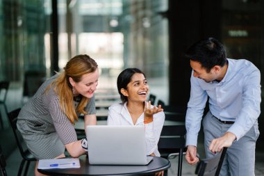 farklı bir takım 3 kişi bir dizüstü bilgisayar etrafında bir tartışma gün açık bir alanda yaşıyorsanız. Gülümse ve konuşmak gibi enerjik ve neşeli vardır.