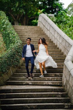 Interracial aşıklar çifti parkta taş merdivenlerden gün boyunca çalıştırın. Bir Hintli Çinli bir kadını evleniyor ve onlar zevk ve neşe içinde merdivenlerden aşağı çalışan.